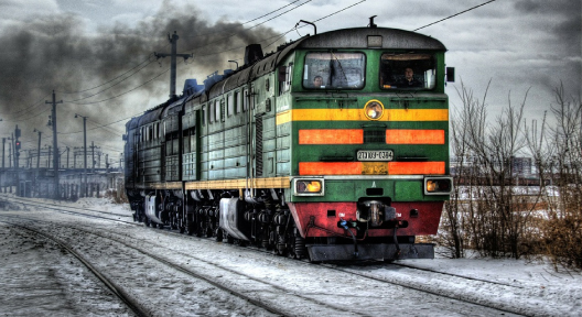 Mööda raudteed lähenev rohelist värvi ja tossav rong.