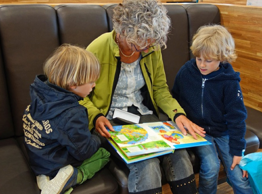 Vanaema lastelastega raamatut vaatamas.